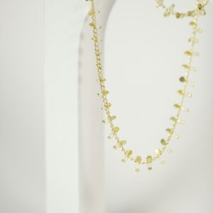 Colar longo de contas amarelo-claras sobre fundo creme