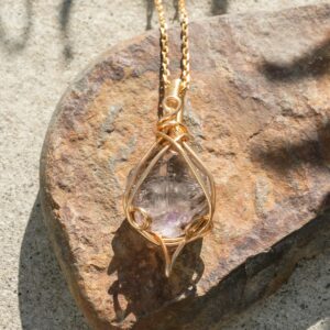 Pingente de quartzo cristal em fio dourado sobre pedra