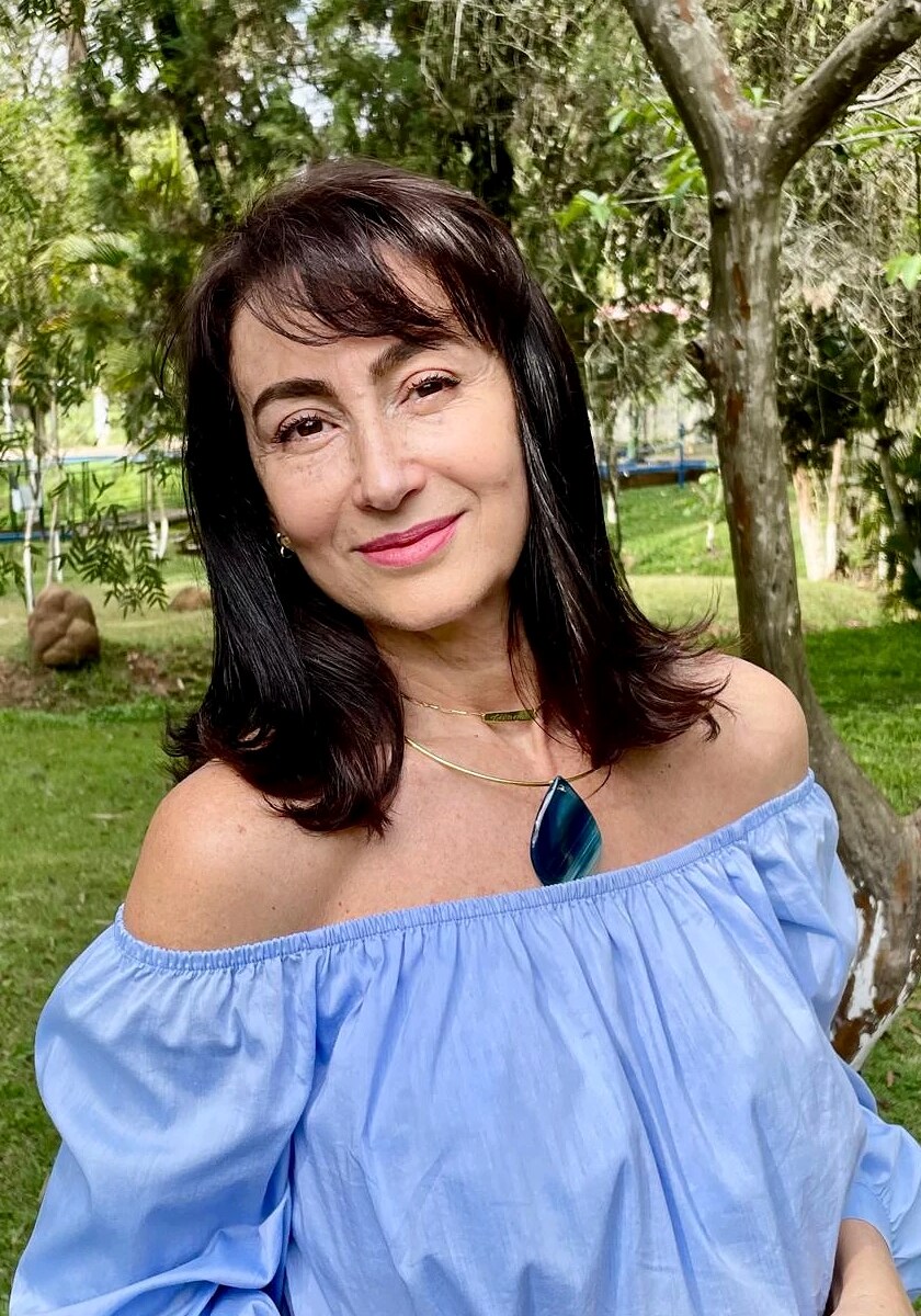 Mulher de blusa azul usando colar dourado com pingente de ágata azul